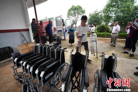 新余市残联工作人员和民进新余市委会医卫专家在罗坊镇陈家村安装残疾人辅助器具。 周亮 摄