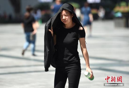 5月17日,重庆气温升至30℃以上,市民将随身衣物顶在头上遮挡烈日。周毅 摄