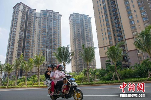 资料图:市民在海口市区某地产项目前路过。 中新社记者 骆云飞 摄