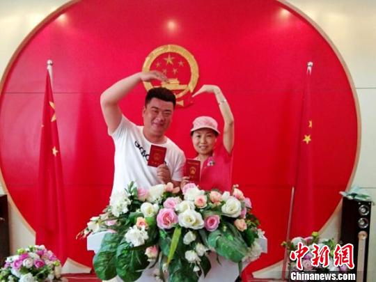 图为拿到结婚证后的新人们摆出姿势秀恩爱。 王秋兰 摄