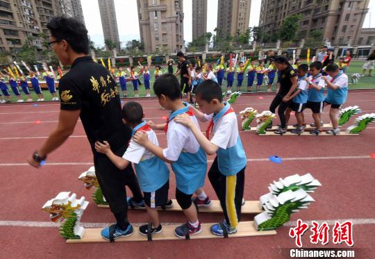 学生们在华侨大学龙舟队的队员们带领下共同体验“旱地龙舟”。 记者刘可耕 摄