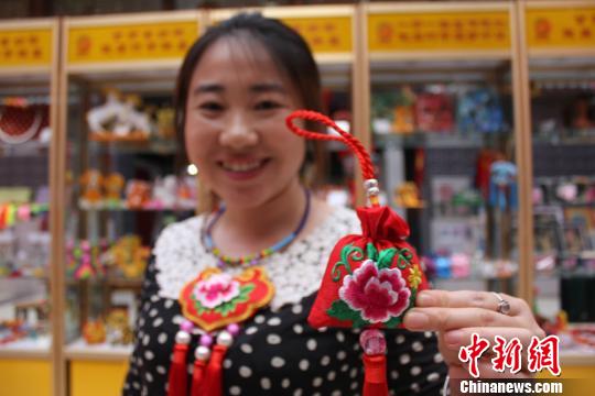 图为在甘肃省妇联陇原巧手体验馆内,工作人员展示新制作的香包。 徐雪 摄