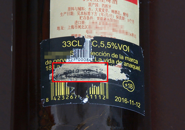 撕开啤酒瓶上的一层标签，里头的生产日期是2013年的。视频截图