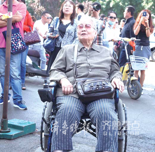 一名78岁的老人自己坐轮椅来到省实验中学考点，看着自己的孙子进考场。