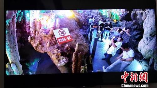 图为一游客在景区游玩时用力踢石钟乳。景区监控视频截图。