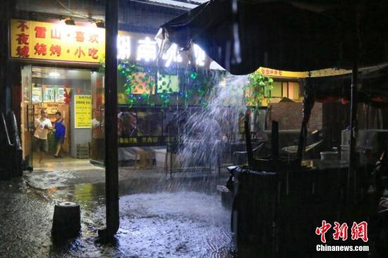 6月10日晚,贵州省雷山县遭受暴雨袭击。据贵州气象局预测,6月10日夜间发布暴雨黄色预警信号,在11日1时升级为红色预警。提醒民众注意防范。图为雷山民众在夜市中避雨。 <a target=\'_blank\' href=\'http://www.chinanews.com/\'>中新社</a>记者 贺俊怡 摄