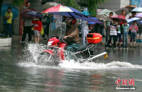 6月12日,贵阳市民骑摩托车在积水路段行驶。<a target=\'_blank\' href=\'http://www.chinanews.com/\'>中新社</a>记者 贺俊怡 摄