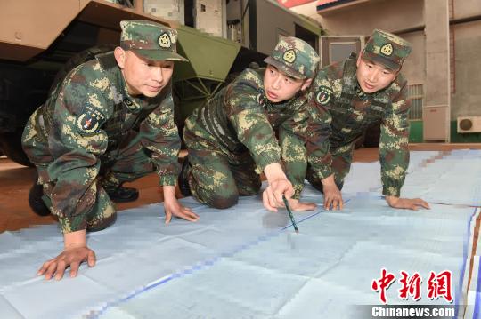 尹东(居中)和连队两位技术骨干推研导弹电路图。 陈双维 摄