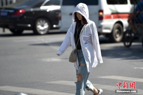 资料图:北京三里屯SOHO附近行人避暑防晒“各显神通”。<a target=\'_blank\' href=\'http://www.chinanews.com/\' >中新网</a>记者 金硕 摄