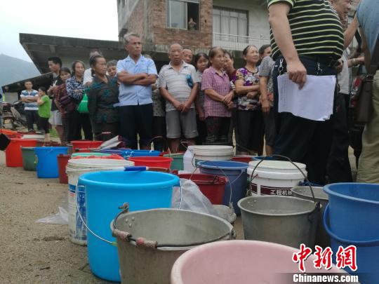 村民拿着各种载具排队领鱼苗。 蒙鸣明 摄