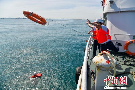 演习中搜救人员发现“落水者”，抛出救生圈救援。　骆云飞　摄