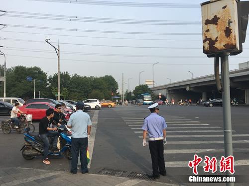6月21日上午,北京仰山桥下十字路口,执勤人员要求非机动车停在停止线后。汤琪 摄