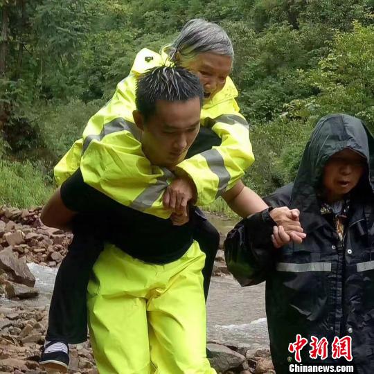 图为：遂昌一位民警将自己的衣服穿在老人身上，并背起老人向安全地带转移。　徐民哲(通讯员) 摄