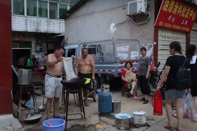  7月2日19时，群英路，因家中被水浸泡，以及停水停电，几家人在路边架锅做晚饭。