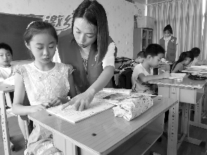 暑期公益班首堂课上,老师在指导孩子做作业 毛晓华 摄