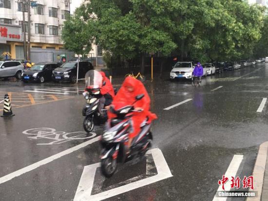 资料图 北京阜成路，市民雨中骑行。 中新网记者 富宇 摄