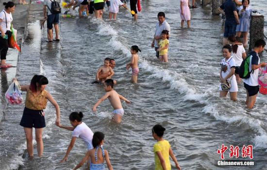 7月4日傍晚,市民们带着小孩在海边戏水消暑。连日来,受副热带高压影响厦门地区持续高温。 张斌 摄