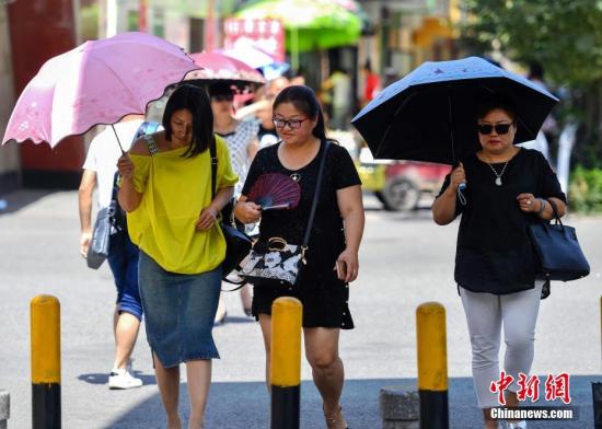 资料图：7月6日，新疆乌鲁木齐市最高温度达到36摄氏度，外出民众打着伞。 中新社记者 刘新 摄