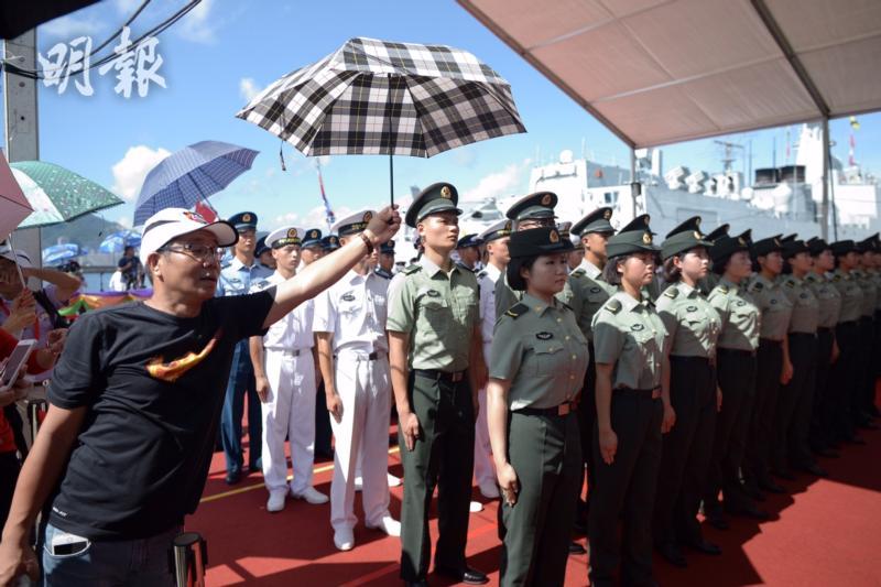  有市民对解放军在烈日下暴晒感到“心痛”，为解放军撑伞。（图片来源：明报）