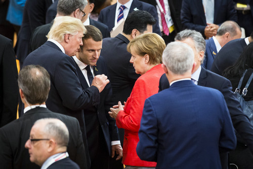  资料图片：7月7日，在德国汉堡，德国总理默克尔（中右）、美国总统特朗普（中左）和法国总统马克龙（中）在二十国集团（G20）峰会期间交谈。新华社发