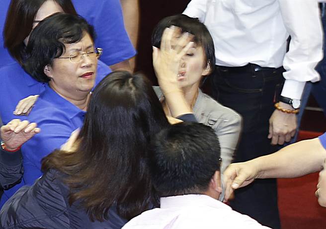 民进党“立委”邱议莹（中后）在抢国民党麦克风时遭国民党“立委”许淑华一掌推打（中背影者）、邱议莹脸部瞬间变形。（图片来源：中时电子报）