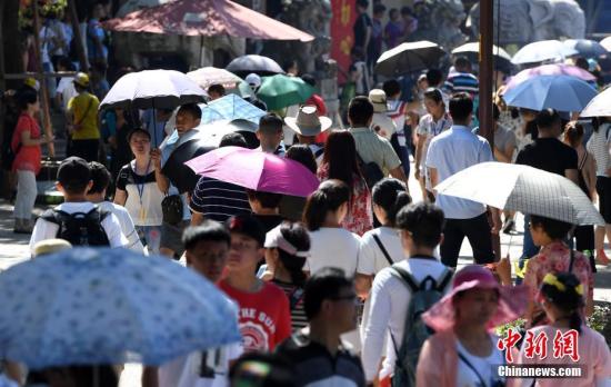 厦门一景点游客们纷纷打伞遮挡烈日。张斌 摄