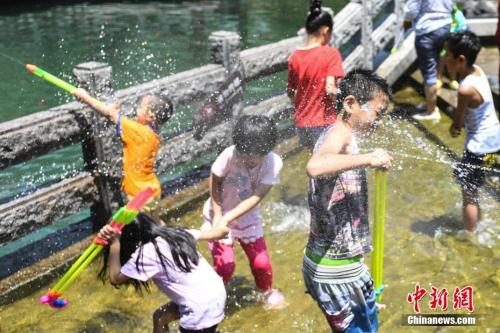 7月11日，几名儿童在山东济南“清泉石上流”池中戏水纳凉。中新社记者 张勇 摄