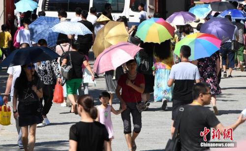 7月12日,厦门一景点游客们纷纷打起伞遮挡烈日。张斌 摄