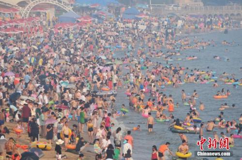 2017年7月12日，青岛市第一海水浴场日迎数万游客前来避暑纳凉。中新社发 王海滨 摄