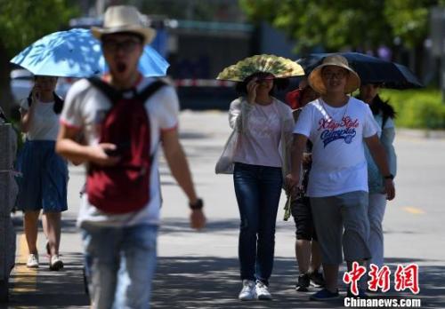 7月13日，厦门市民行走在热浪滚滚的路面上。张斌 摄