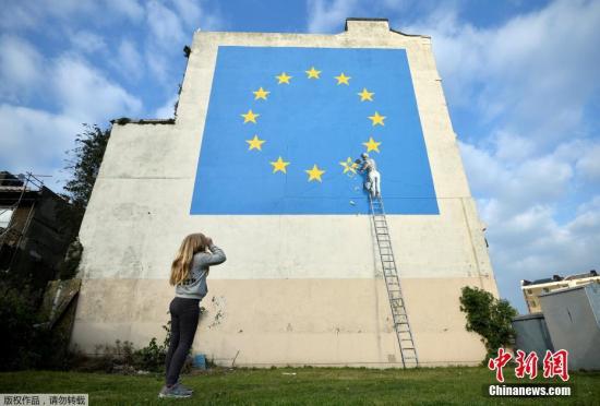 资料图：2017年5月7日，英国多佛，一名街头艺术家班克西创作了一幅画，画面中一名工人正从欧盟12星旗帜上抹掉一颗星，寓意着英国将脱离欧盟。