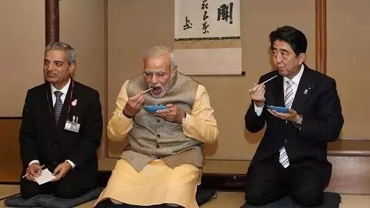 ▲资料图片：2014年9月1日，日本东京，印度总理莫迪和日本首相安倍一起吃茶饼。（彭博社）