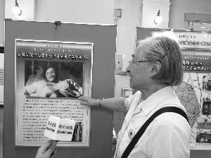 南京大屠杀幸存者李秀英女儿陆玲在图片前介绍母亲的遭遇