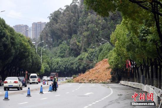 7月14日，工作人员正在对发生滑坡路段的行进车辆进行交通指挥。当日，昆明市连日来的降雨，致穿金路进城方向伍家村路段发生山体滑坡。中新社记者 李进红 摄