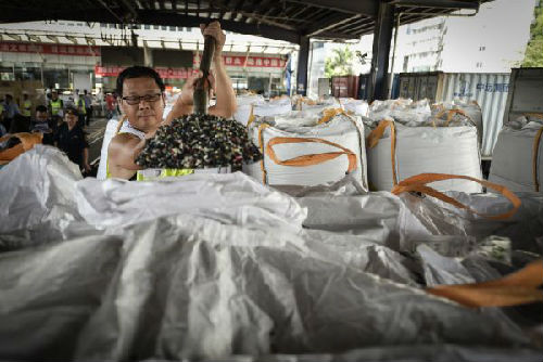 2016年6月2日，深圳海关工作人员拆开包装，展示查获的偷运入境的固体废弃物。（新华社）