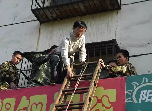 2010年3月，河南洛阳，一名光脚的青年男子从4楼窗户爬下时被困，警方乐成将其救下。 东方IC 资料图