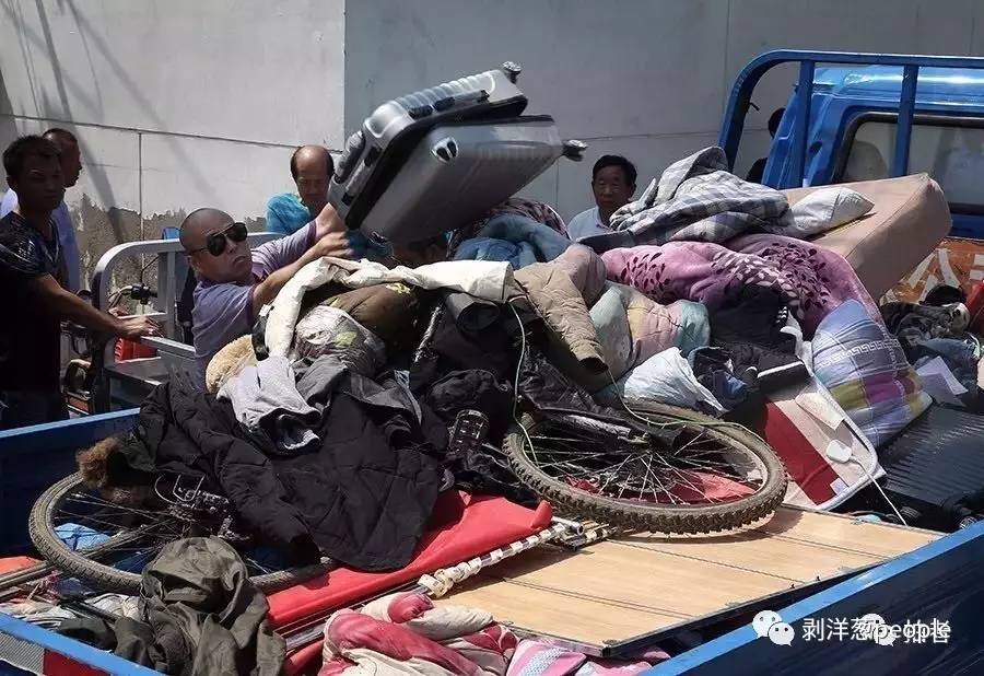 联合执法人员雇佣的搬家公司员工,正将传销人员留下的生活物品运走。