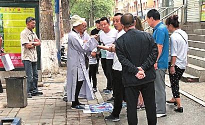 穿长袍看相男子身边围了很多人,发现记者拍摄视频,圆圈中的男子对记者进行了殴打 新文化记者 文直 摄