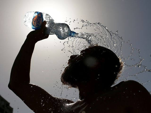 　7月24日，马其顿首都斯科普里，烈日下，一名男子用瓶子给身体浇水降温。（新华/路透）