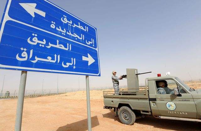  沙特士兵在阿尔阿尔市附近的沙特伊拉克边境处巡逻，道路指示牌上写着：通往杰迪代（上）；通过伊拉克（下）。（新华/法新）