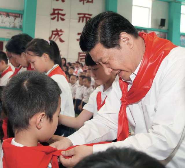 2014年5月30日，习近平来到北京市海淀区民族小学参加庆祝“六一”国际儿童节活动。这是习近平在少先队入队仪式上，为新少先队员系上红领巾   鞠鹏摄/本刊