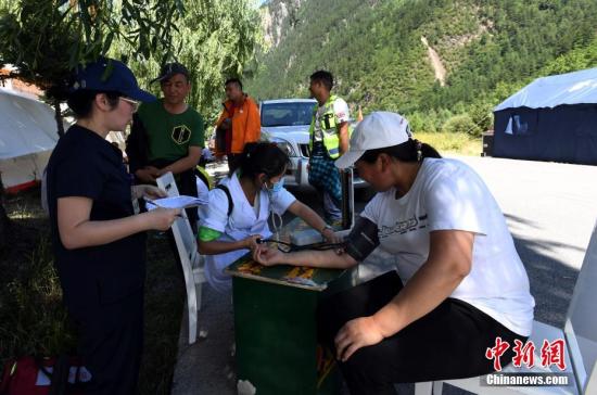 8月13日,记者走进九寨沟景区荷叶寨村民集中安置点,记者看到受灾民众已经住进暂时安置的帐篷内,生涯逐渐恢复正常。图为为村民丈量血压。 安源 摄