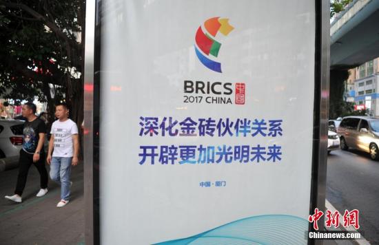 8月24日,厦门市民从“金砖”的标语旁经过。厦门喜迎会晤的气氛日渐浓厚。金砖国家领导人第九次会晤将于9月3日至5日在福建厦门举行。 <a target=\'_blank\' href=\'http://www.chinanews.com/\'>中新社</a>记者 张斌 摄