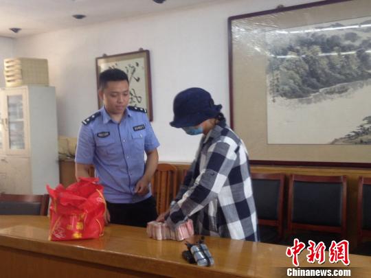 李女士从民警手中领回10万元现金。 晨晓 摄
