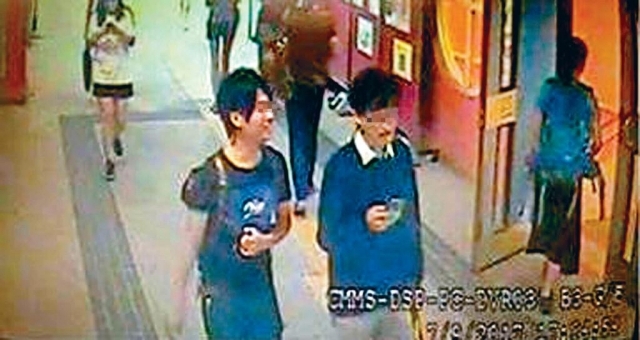 两名涉事者年约二十多岁，其中一人戴眼镜，穿白恤衫、深色毛衣及浅色长裤；另一人穿深色T恤及长裤，面露笑容。（图源：香港头条日报）