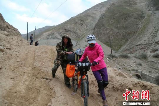 图为武警官兵帮助骑行游客从便道翻越达坂。 石开群 摄