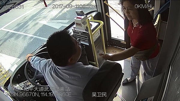 一名身穿红色上衣的女士向司机拍肩致谢。