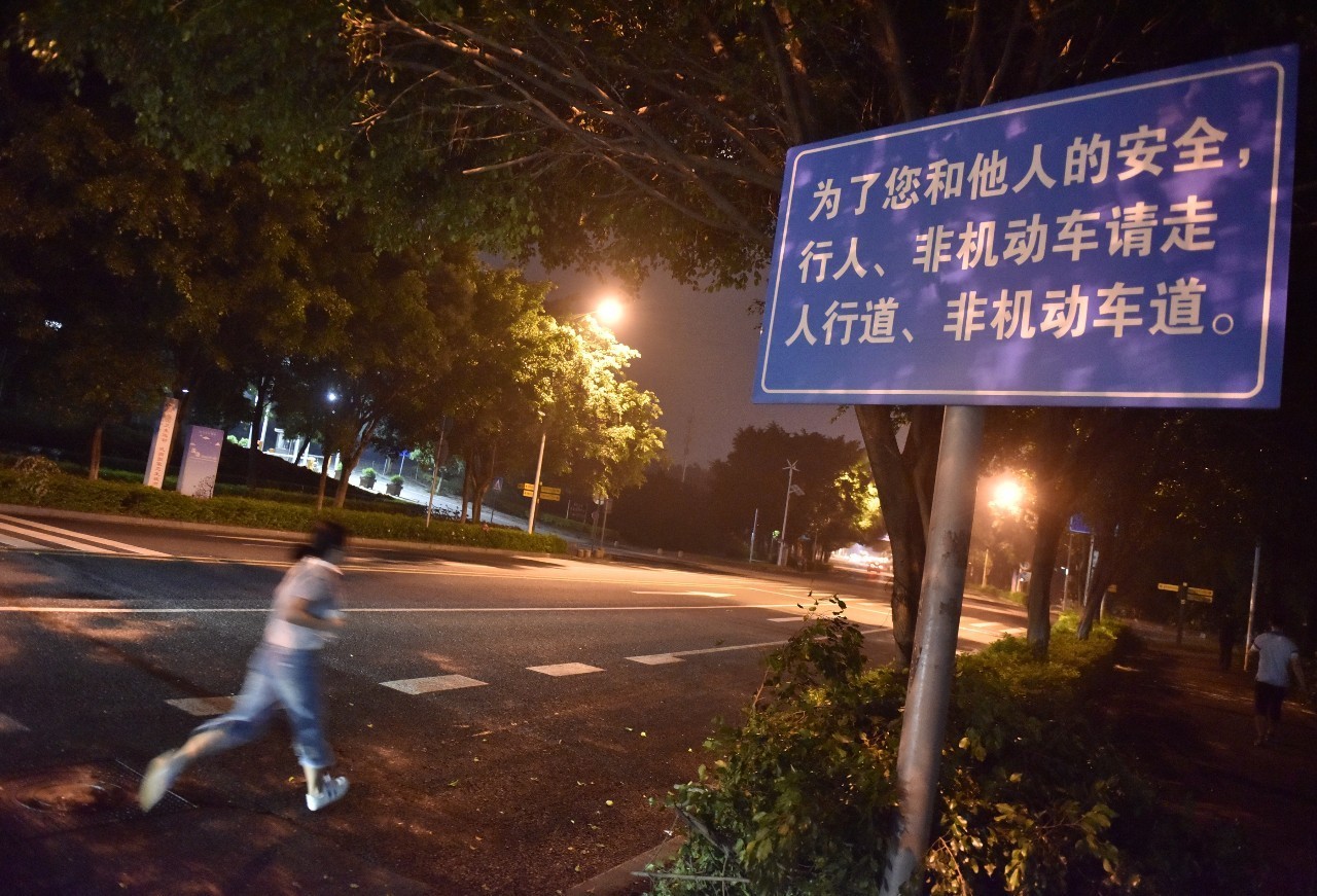 大学城内环部分路段竖有交通安全警示牌,然而还是有市民在机动车道飞奔。 信息时报记者 朱元斌 摄