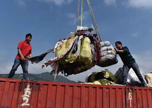  资料图：在深圳海关开展的一次“洋垃圾”销毁行动中，工作人员在搬运走私废旧衣物。（马来西亚《星洲日报》网站）