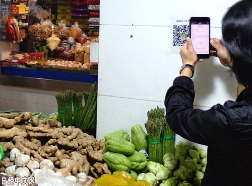 市民在菜市场买菜用手机支付。（《日本经济新闻》网站）